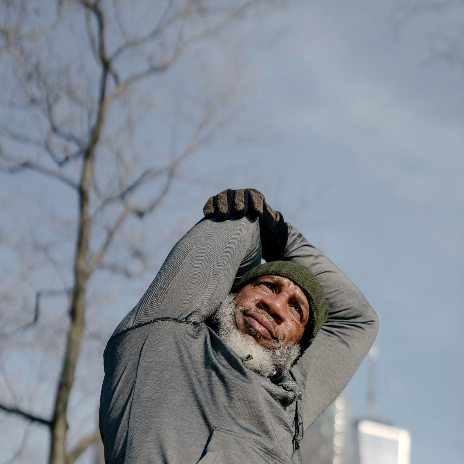 A grey-bearded man in a grey sweater outdoors in a winter park