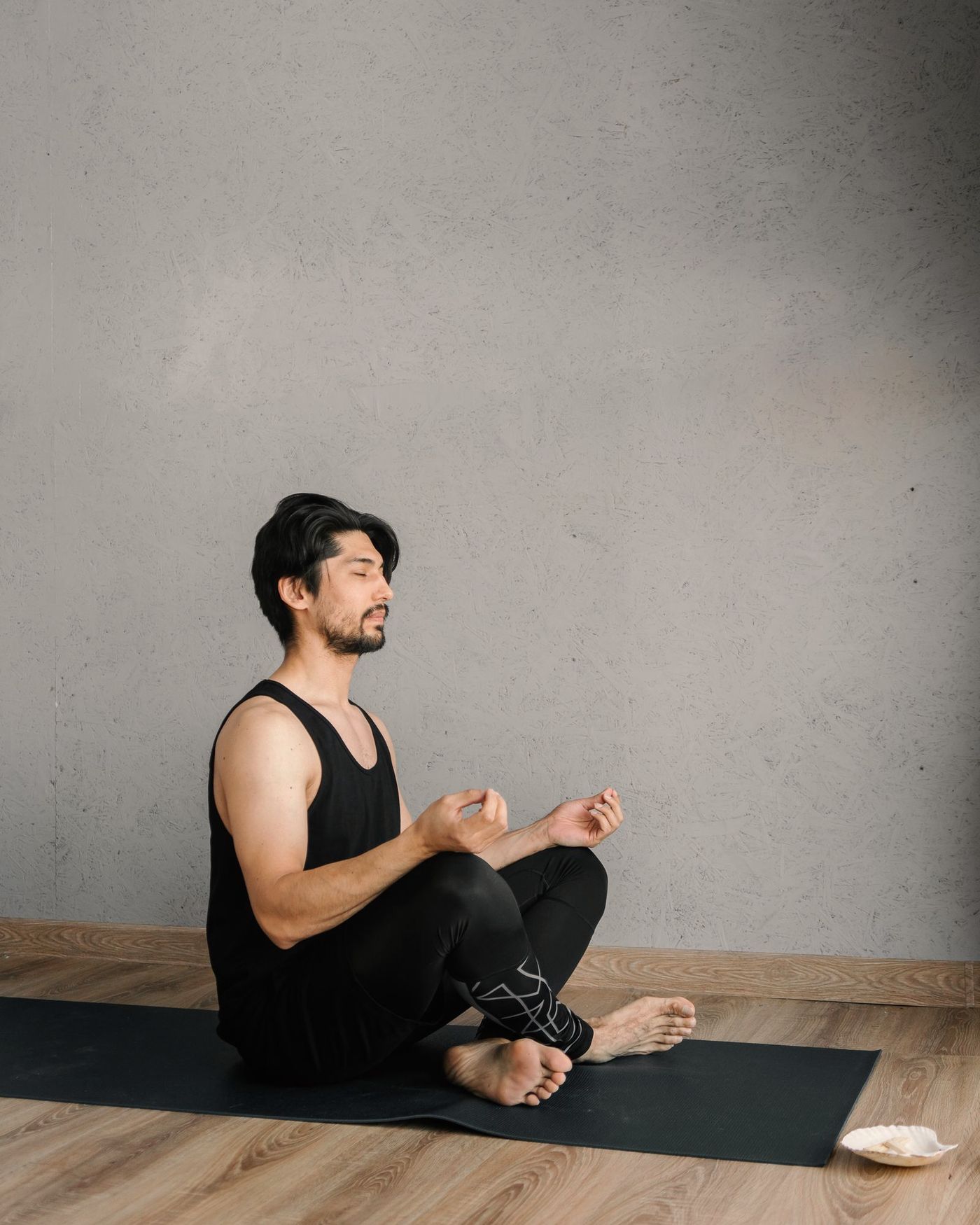 A man in a dark set seated on a yoga mat